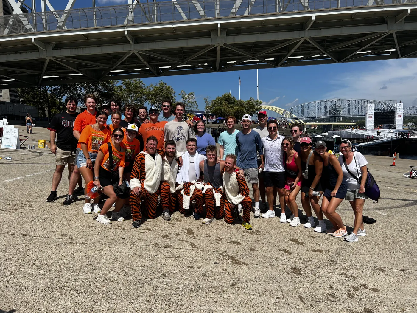 Large group of friends and family in tiger costumes and orange shirts posing together.