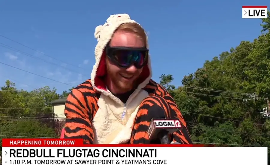 A team member in a tiger costume and sunglasses during a live TV news segment.